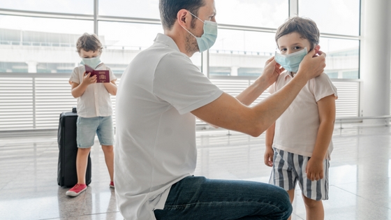 Perhe matkustaa covid 19 aikana maskeissa.